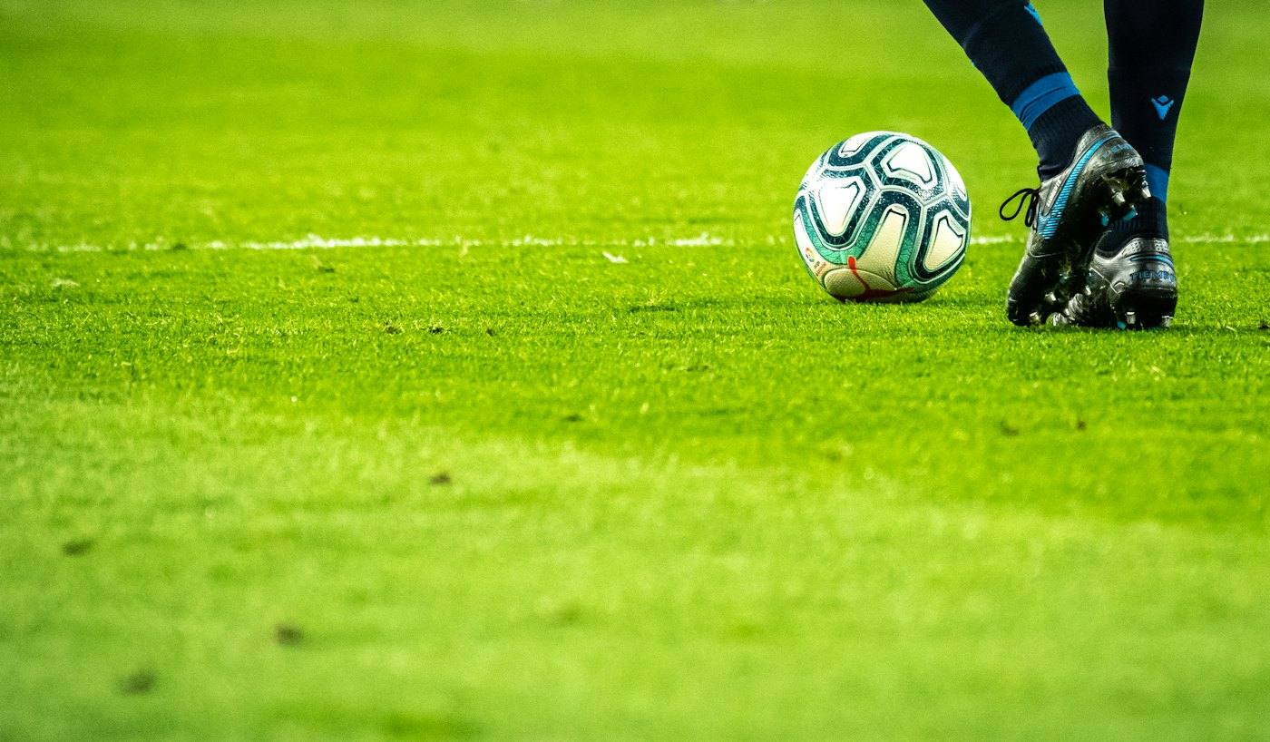 Teen playing soccer on a grass field